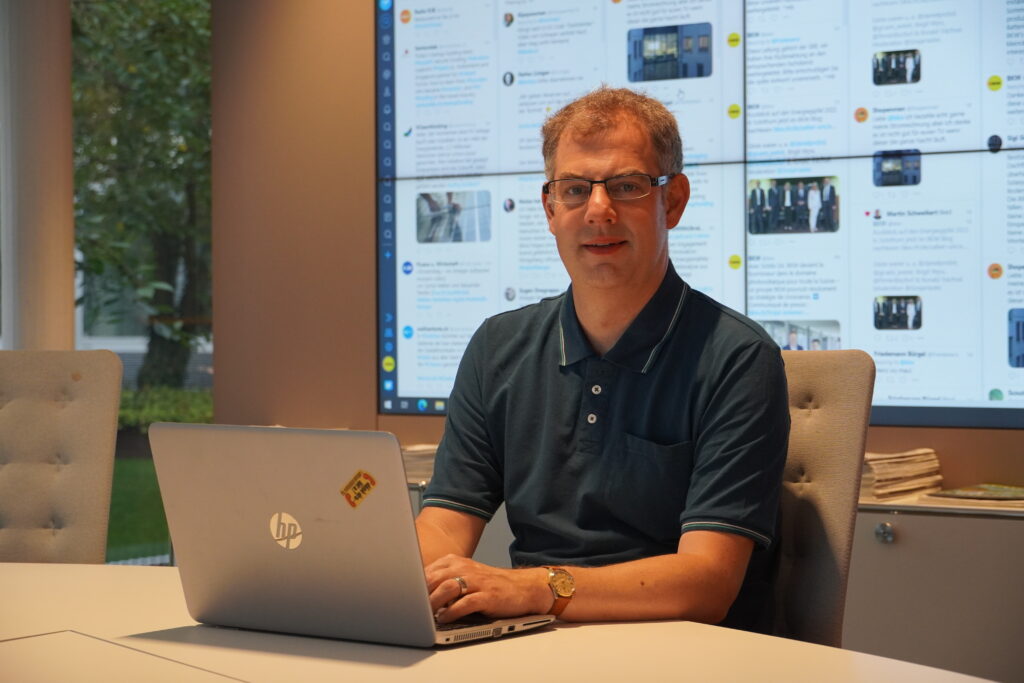 Person sitzt vor einer Videowall an einem Bürotisch